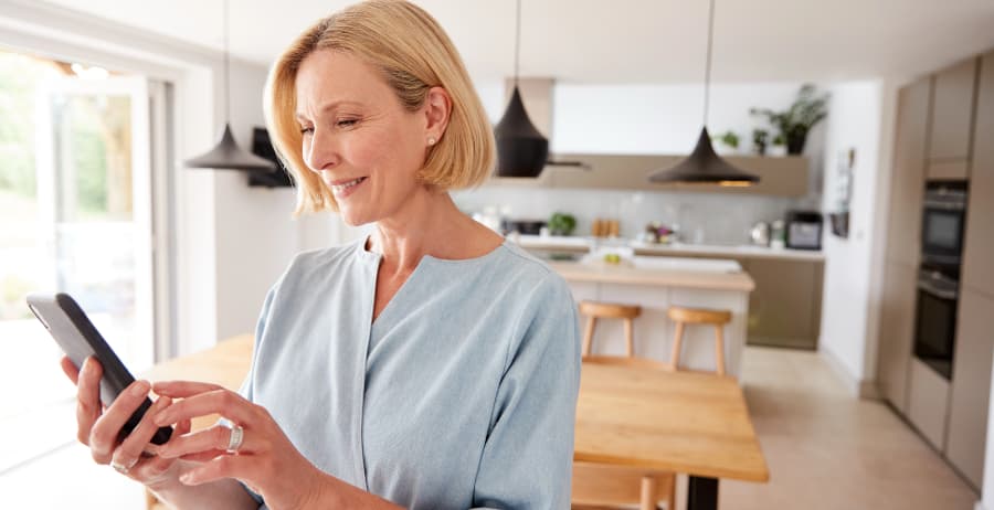 Homeowner using a mobile device in a room filled with sunlight
